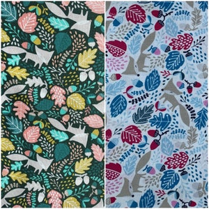 May include: Two fabric swatches with a repeating pattern of stylized foxes, leaves, and acorns. The fabric on the left is a dark green background with white, pink, and yellow accents. The fabric on the right is a light blue background with white, pink, and blue accents.
