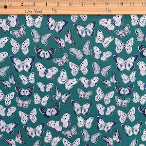 May include: Teal fabric with a white and black butterfly pattern. The butterflies are scattered randomly across the fabric.