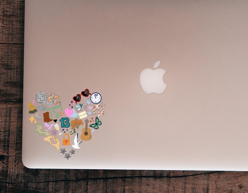 May include: A heart-shaped sticker design filled with various colorful illustrations. The design includes a disco ball, cowboy boot, sunglasses, a clock, a guitar, a butterfly, and the number 13. The sticker is placed on a laptop.