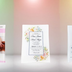 May include: Three clear acrylic plaques with floral designs and personalized text. The first plaque features a baby photo and the text "Welcome to the world - 02.24.2019 Olivia Camille". The second plaque features a wedding invitation with the text "Diana Lawson & Robert Mayer September 8, 2018". The third plaque features a save the date card with the text "Save the Date for the wedding of Emily Taylor & Conner Friday October 8, 2018".