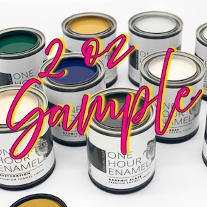 May include: A collection of small paint cans in various colors, including green, blue, and white. The cans are labeled "One Hour Enamel" and "2 oz Sample" is written across the image in pink and yellow.