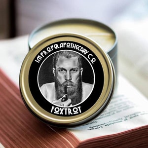 May include: A gold tin with a black label featuring a man with a beard and a pipe. The label reads "Improper Apothecary Co." and "Fox Trot".
