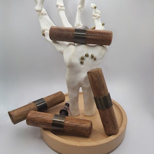 May include: Four wooden cabinet knobs with brass accents. The knobs are displayed on a wooden platform. The text "UNDEAD HARDWARE By Undead Furniture Co" is visible at the bottom of the image.