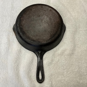 May include: A vintage Wagner Ware Sidney 0 cast iron skillet. The skillet is black with a long handle and a circular cooking surface. The words "WAGNER WARE SIDNEY 0" are embossed on the top of the skillet.