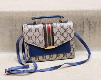 Bolso con monograma, detalles en azul marino y una llamativa raya: un estilo elegante y estructurado para la transición del día a la noche.