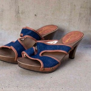 May include: A pair of blue denim and brown leather heeled sandals with a wooden platform.