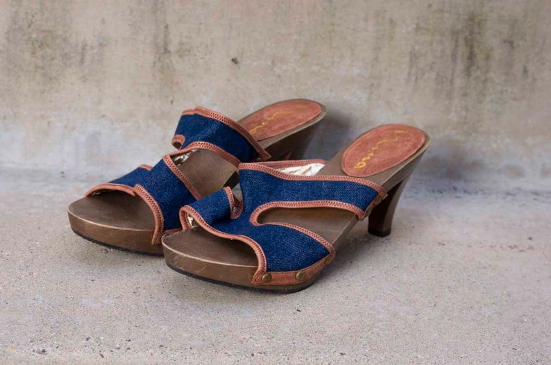 May include: A pair of blue denim and brown leather heeled sandals with a wooden platform.