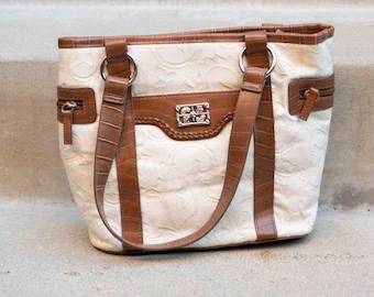 Bolso color crudo con detalles marrones y sutiles adornos: elegante y versátil para el uso diario.