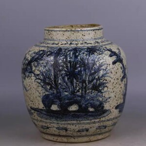 Peut inclure: Un vase rond en céramique avec un fond blanc cassé moucheté et un motif paysager bleu. Le vase présente une illustration détaillée d'arbres et de feuillages, avec un bord et une base bleu foncé. Le design général rappelle la poterie traditionnelle.