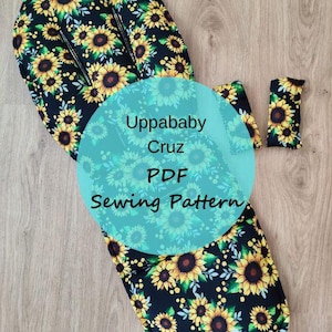 May include: A black and yellow sunflower patterned fabric, with the text "Uppababy Cruz PDF Sewing Pattern" on a teal circle. The fabric is likely for a baby stroller or similar item. The image shows multiple pieces of the fabric.