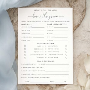May include: A white card with the text "How Well Do You Know the Groom" in elegant script. The card features fill-in-the-blank questions about the groom's preferences and personal details, perfect for a bridal shower game.