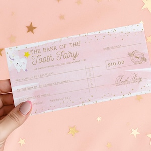 May include: A pink and gold check from "The Bank of the Tooth Fairy" with a cartoon tooth illustration. The check is for $10.00 and includes fields for the recipient's name and the amount in words. Gold star confetti decorates the background.