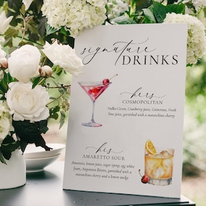 May include: A drinks menu with the words "Signature Drinks" in cursive. It features watercolour illustrations of a Cosmopolitan and an Amaretto Sour, with ingredients listed. The sign is surrounded by white flowers.