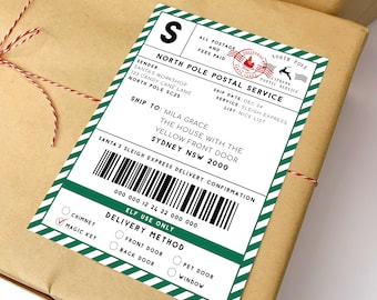 Może przedstawiać: Brązowa paczka z zielono-białą etykietą z North Pole Postal Service. Etykieta zawiera tekst "Santa's Workshop" i "Mila Grace". Metoda dostawy oznaczona jako "Magic Key".