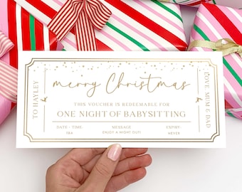 May include: A white and gold Christmas voucher with the text "merry Christmas" and "One Night of Babysitting". The voucher is held in a hand, with wrapped gifts in the background.