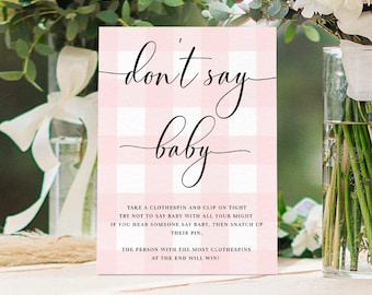 May include: Pink and white gingham patterned card with the text "don't say baby" in black cursive font. The card includes instructions for a game where guests take a clothespin and try not to say the word "baby".