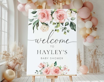 May include: Welcome to Hayley's Baby Shower sign with pink and white floral design. The sign is on an easel.