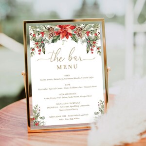 May include: A gold framed bar menu with a festive Christmas theme. The menu features a floral design with red poinsettias, pinecones, and greenery. The menu lists beer, wine, non-alcoholic drinks, and signature cocktails.