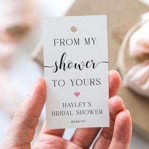 Könnte beinhalten: Weißer Geschenkanhänger mit schwarzem Text, der "From my shower to yours" mit einem rosa Herzen und dem Text "Hayley's Bridal Shower 06.06.YY" lautet