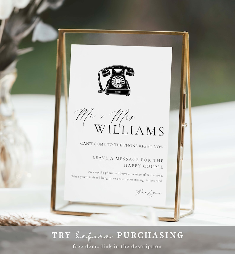 May include: A white rectangular sign in a gold metal frame featuring a black illustration of a rotary telephone and the text: Mr + Mrs WILLIAMS, CAN'T COME TO THE PHONE RIGHT NOW, LEAVE A MESSAGE FOR THE HAPPY COUPLE, and instructions for guests.