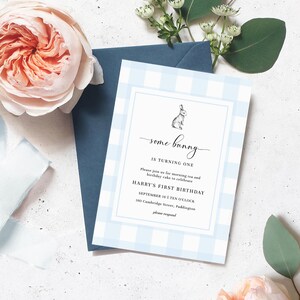 Może przedstawiać: Niebieskie zaproszenie w kratkę vichy z napisem "some bunny is turning one" i małą ilustracją kr&oacute;lika. Zaproszenie jest na pierwsze urodziny Harry'ego i zawiera datę, godzinę i miejsce. Granatowa koperta i r&oacute;żowe kwiaty w tle.