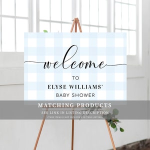 Może przedstawiać: Witamy znak na baby shower na drewnianym sztaludze. Znak ma jasnoniebieskie i białe tło w kratkę vichy ze słowem "welcome" w eleganckim czarnym skrypcie. Znak brzmi "To Elyse Williams' Baby Shower".