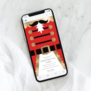 May include: A smartphone displays a Christmas Eve party invitation. The design features a red and gold nutcracker soldier illustration with a black mustache and white details. The invitation text is in a serif font.
