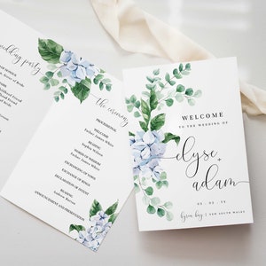 May include: Wedding ceremony programme with a watercolour floral design featuring blue hydrangeas and green leaves. The programme lists the processional, readings, and other details of the ceremony. The welcome sign features the couple's names, "Elyse + Adam", and the wedding date and location.
