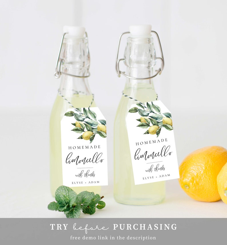 May include: Two small glass bottles filled with a yellow liquid, each with a white tag attached. The tags feature a watercolor illustration of lemons and leaves, and the text "HOMEMADE limoncello with thanks ELYSE ADAM".