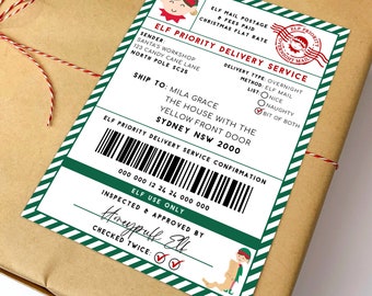 Może przedstawiać: Prostokątna zielono-biała etykieta "Elf Priority Delivery Service" na brązowej paczce. Etykieta zawiera tekst, taki jak "Santa's Workshop", "Mila Grace" i kod kreskowy. Ma również pieczątkę z napisem "Overnight Mail".