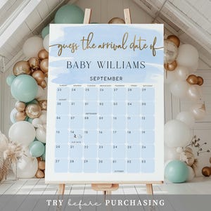 Op de afbeelding: Een blauw en wit aquarel-achtig babyshower-spelbord met gouden letters. Het bord zegt "raad het aankomstdatum van Baby Williams" en heeft een kalender met de data september en oktober.