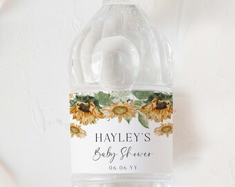 Könnte beinhalten: Transparente Plastikwasserflasche mit weißem Deckel. Das Etikett trägt den Text "HAYLEY'S Baby Shower" und ein Blumendesign aus Sonnenblumen und grünen Blättern. Das Datum "06.06.YY" ist ebenfalls auf dem Etikett aufgedruckt.