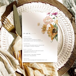 May include: A menu with a floral design featuring sunflowers and other flowers. The menu lists appetizers, starters, main courses, and desserts. The text on the menu includes: Antipasto Platters, Farmhouse fresh greens garden salad, Twice-cooked shoulder of lamb, Honey chicken, crispy speck, Tahitian Vanilla sponge.