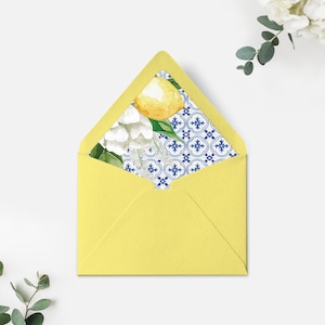 Puede incluir: Un sobre amarillo con un diseño de patrón azul y blanco con limones y flores blancas. El patrón recuerda a los azulejos tradicionales portugueses.