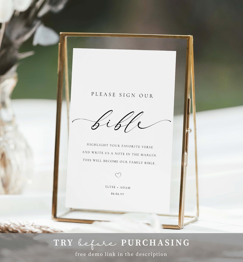 May include: A white sign with gold trim in a gold frame, with the text "PLEASE SIGN OUR bible" in black cursive font. The sign also includes the text "HIGHLIGHT YOUR FAVORITE VERSE AND WRITE US A NOTE IN THE MARGIN. THIS WILL BECOME OUR FAMILY BIBLE." and "ELYSE ADAM 06.06.VY".