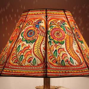 May include: A white lampshade with a colourful floral and bird design. The lampshade is decorated with red, orange, yellow, green, and blue paint.
