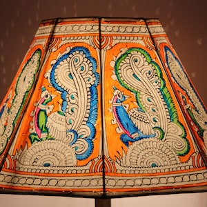 May include: A lampshade with a colorful, hand-painted design featuring peacocks and intricate patterns. The lampshade is made of paper and has a white background with orange, blue, green, and pink accents.