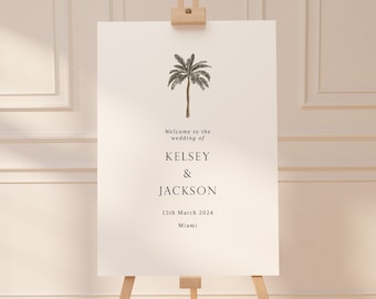 May include: Welcome to the wedding of Kelsey & Jackson, 15th March 2024, Miami. A white sign with black text and a palm tree illustration.