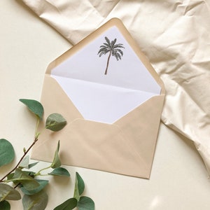 May include: A beige envelope with a white inner flap. The inner flap has a simple black and gray illustration of a palm tree.