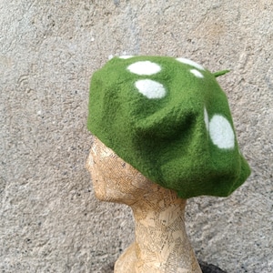 May include: A green beret with white polka dots. The beret is made of felt and has a soft, fuzzy texture.