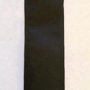 May include: A black fabric rectangle with stitched edges. The fabric is smooth and has a slight sheen.