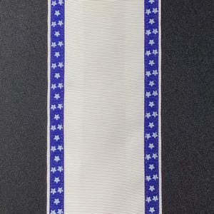 May include: White ribbon with a blue star pattern along the edges. The ribbon has a ribbed texture and is displayed against a dark background. The blue star pattern is a repeating design. This ribbon is suitable for crafts and decorations.