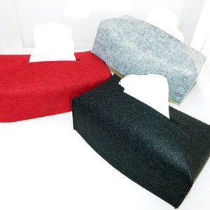 Könnte beinhalten: Drei rechteckige Taschentuchbox-Hüllen aus rotem, grauem und schwarzem Filz. Jede Box hat eine rechteckige Öffnung zur Ausgabe von Taschentüchern. Weiße Taschentücher sind in jeder Box sichtbar. Die Boxen stehen auf weißem Hintergrund.