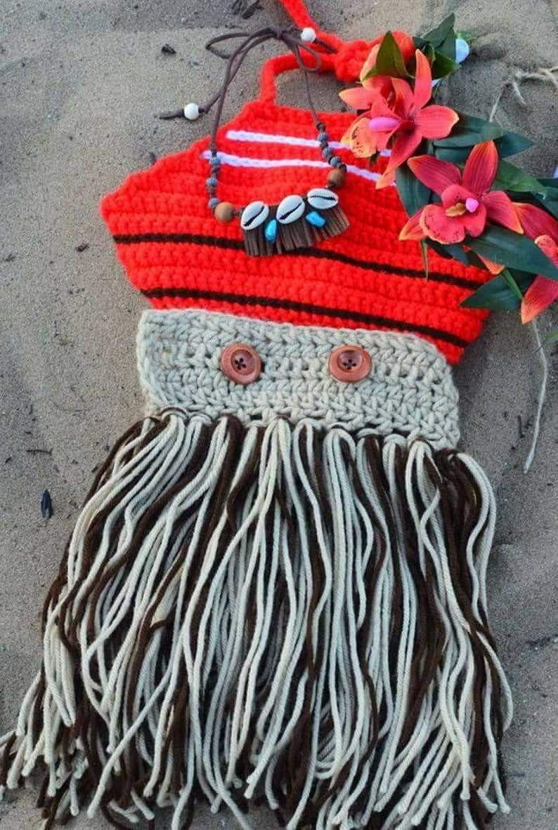 May include: A handmade crochet costume in the style of a Polynesian princess. The top is red with black stripes, and the skirt is made of brown and white yarn. The costume includes a necklace with shells and wooden beads, and is decorated with red flowers.