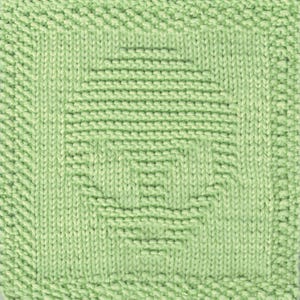 May include: A green knitted square with a textured pattern. The pattern is made up of rows of knit and purl stitches, creating a geometric design.
