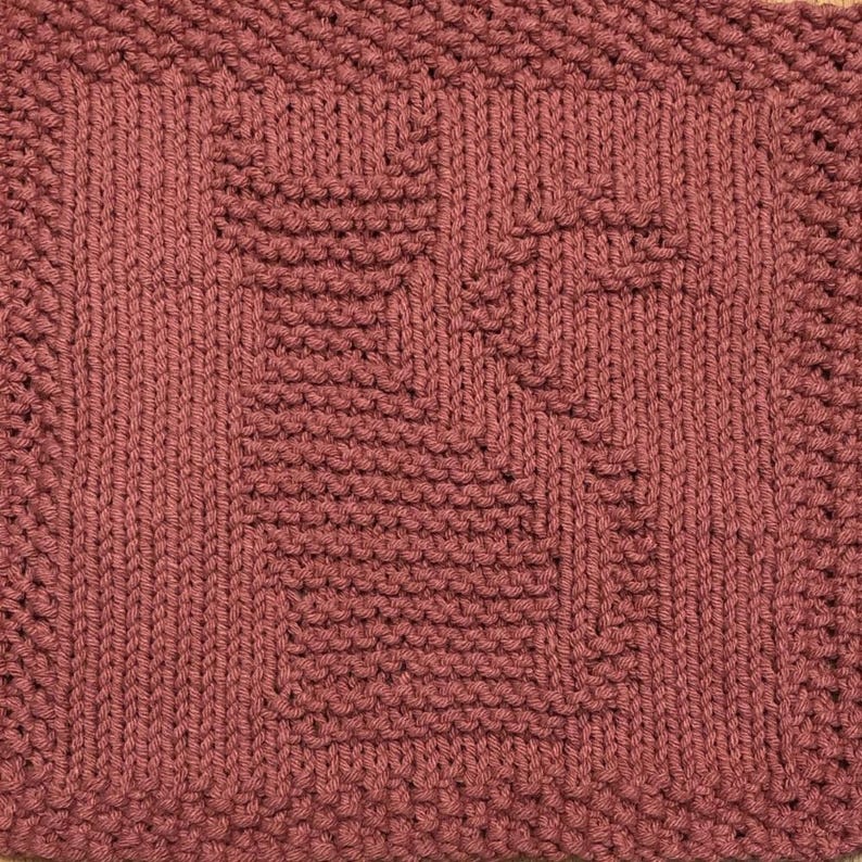 May include: A knitted dishcloth in a deep burgundy color with a geometric pattern.
