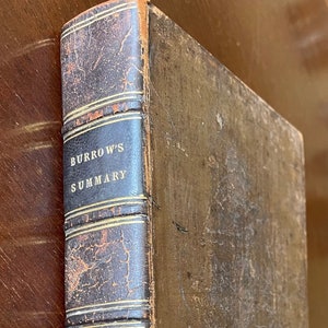 May include: A vintage, brown leather-bound book with the title "Burrow's Summary" embossed on the spine. The book is worn and has a faded gold design on the spine.