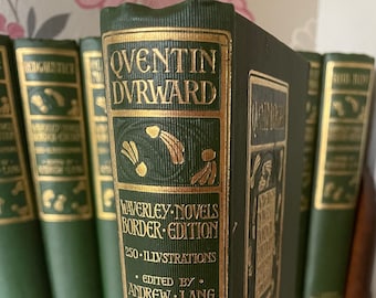 Op de afbeelding: Een groen hardback boek getiteld "Quentin Durward" met gouden letters. Het boek maakt deel uit van een set "Waverley Novels Border Edition" met 250 illustraties, bewerkt door Andrew Lang. Het boek is uitgegeven door Macmillan & Co. in Londen.