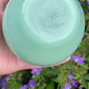 K&ouml;nnte beinhalten: Eine hellgr&uuml;ne Glasschale mit glatter, gl&auml;nzender Oberfl&auml;che. Die Schale ist rund und hat einen leichten Rand.