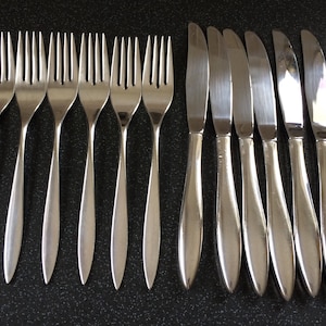 Könnte beinhalten: Ein Set aus 12 silberfarbenen Besteckteilen, darunter Gabeln und Messer. Das Besteck ist in zwei Reihen angeordnet, die Gabeln in der oberen Reihe und die Messer in der unteren Reihe.
